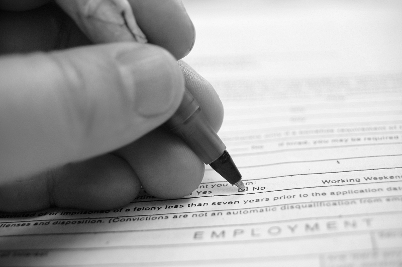 Photo of hand filling out application form with pen