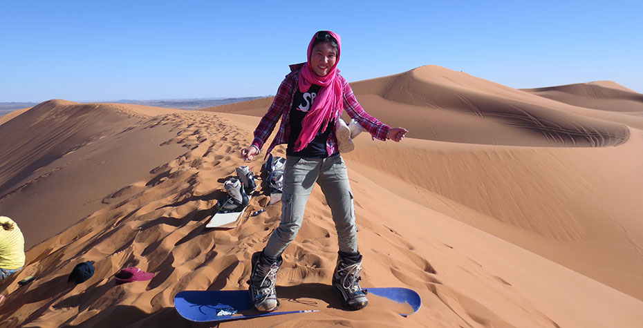 Kathy Long on a "sandboard" about to slide down a desert dune