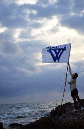raising a Wellesley flag along a windy shore