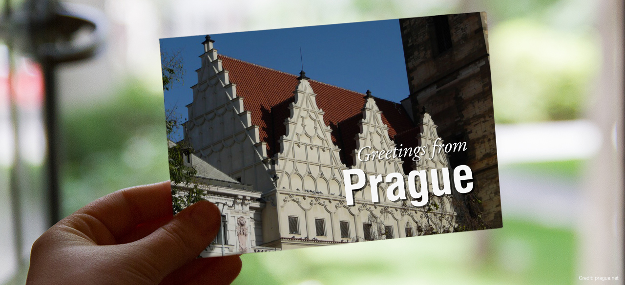 Hand holds a postcard that reads "Greetings from Prague"