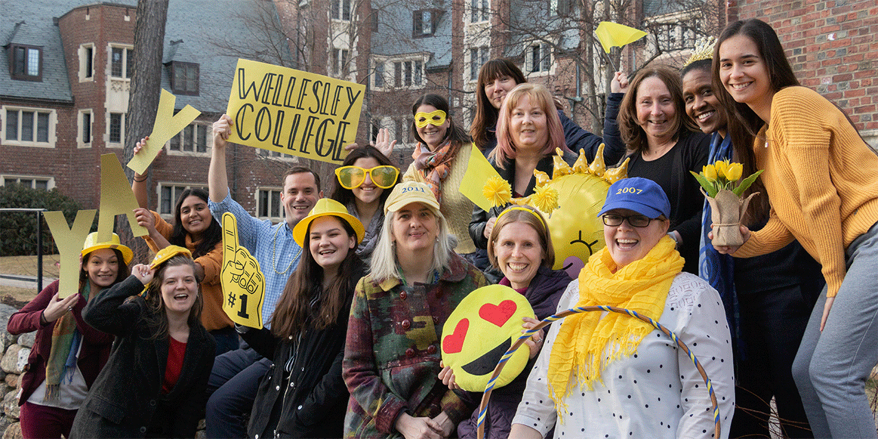 Admissions staff members hold up yellow signs and wear yellow clothing