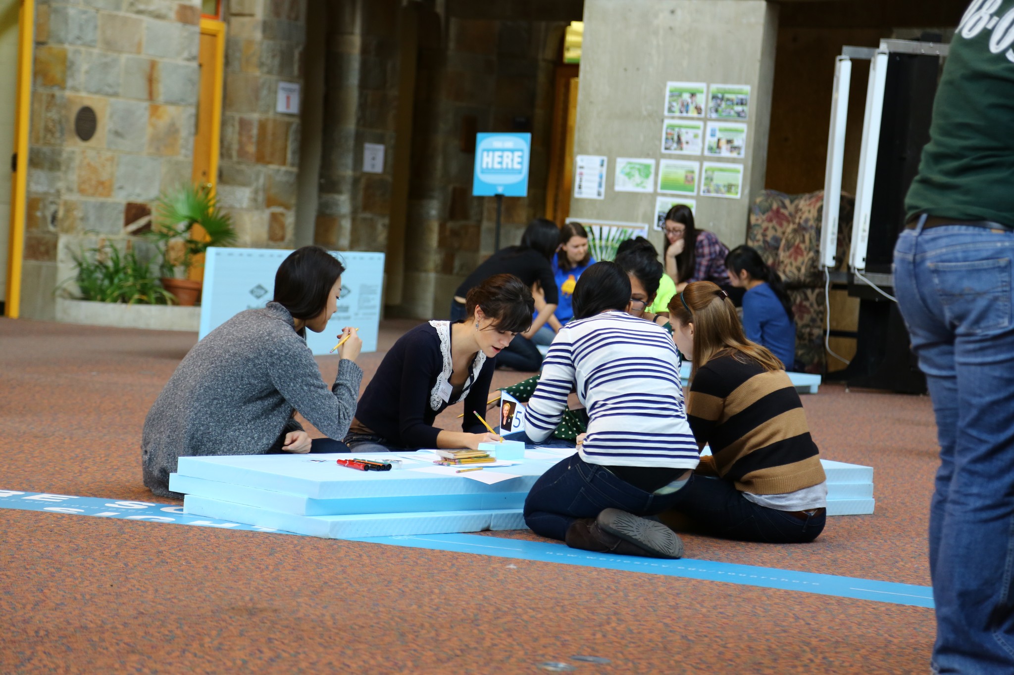 Wellelsey students gatherered around blue foam pieces on the floor of the Farroll Focus in the Science Center, writing and talki