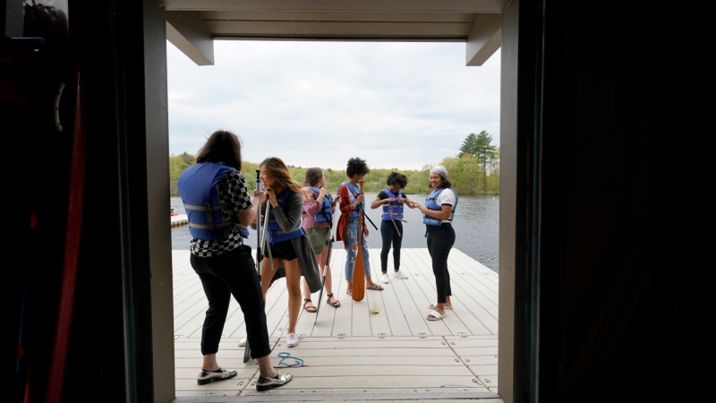 students in lifevests as seen through the boathouse doorway