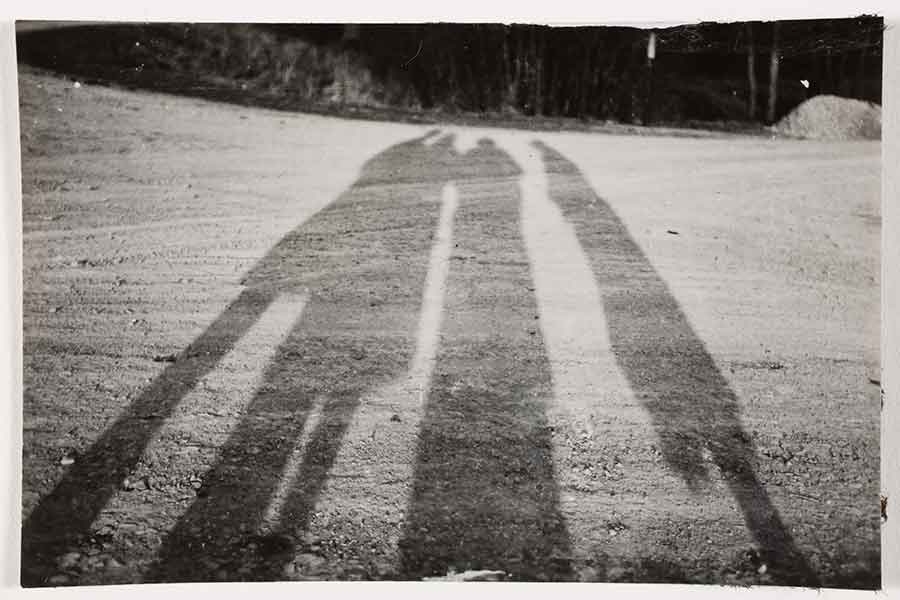black and white image of three people's shadows on the ground