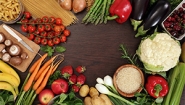 Kristin Butcher, Professor of Economics, on SNAP Benefits Healthy foods circle a space on a table, a quote from Prof. Kristin Butcher is overlaid