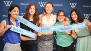 Final Hours of the 2016 Participation Challenge Alumnae hold "Wellesley Welcome" signs in front of a blue backdrop