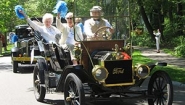 white haired alums wave from antique car