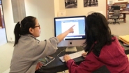 two students work at a computer in Wellesley library