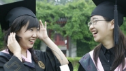 two Chinese students trying on graduation caps