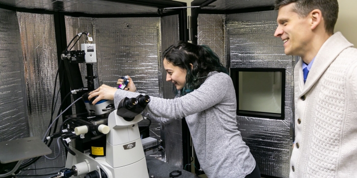 Ellie Gibbs ’22 Can See Whole Worlds in a Single Yeast Cell A student works with a microscope as a professor looks on