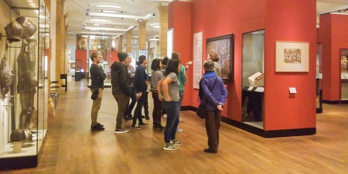 Students Document Wintersession in Berlin Using Instagram Stories A group of female students stand looking at a painting on a red wall in the German Historical Museum.