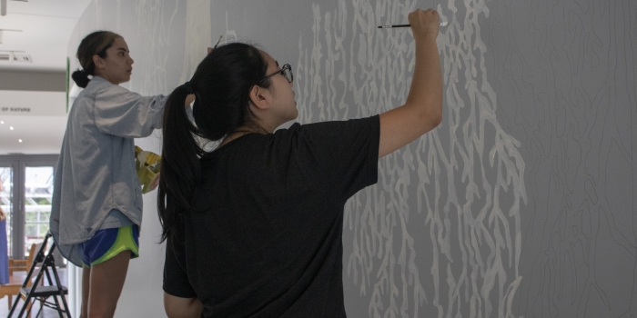 Students and Faculty Paint Mural in New Global Flora Conservatory Two students work on a walled mural.