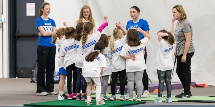 Blue Student-Athletes Coach Local Girls to Celebrate National Girls and Women in Sports Day A group of young girls stand with Wellesley student athletes and a coach