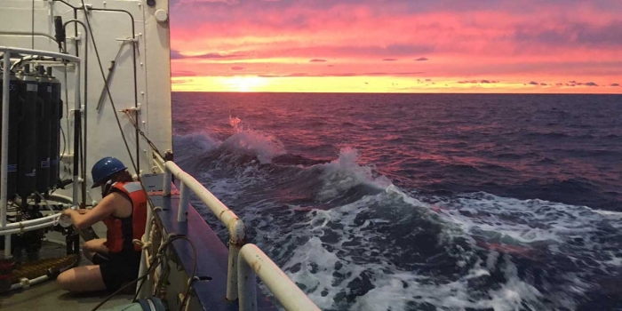 Wellesley Professor Examines the Ocean’s Response to Climate Change A professor gathers water samples on a boat mid voyage. Photo taken at sunset.