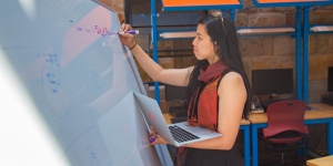 In Essay for Refinery29, Wellesley Senior Explains How She Learned to Love Computer Science A student stands by a white board, writing and holding a computer
