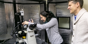 Ellie Gibbs ’22 Can See Whole Worlds in a Single Yeast Cell A student works with a microscope as a professor looks on