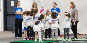 Blue Student-Athletes Coach Local Girls to Celebrate National Girls and Women in Sports Day A group of young girls stand with Wellesley student athletes and a coach