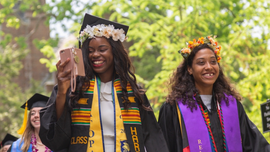 Two members of the class of 2019 walk into the tent for the commencement exercises.