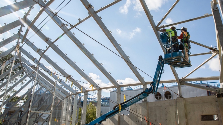 A construction team lifts the final beam into place at the Global Flora greenhouse on Science Hill.