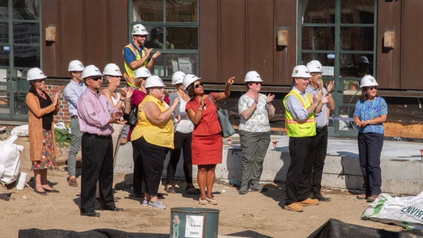 Wellesley community members and the construction team looks on as the beam is lifted into place.