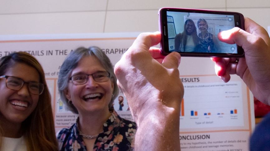 A student and her advisor take a photo with a smart phone