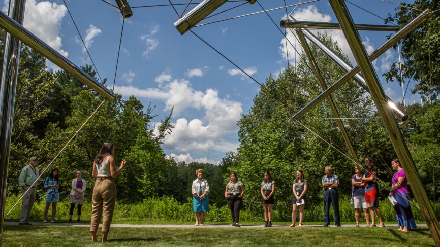A student describes a sculpture on campus outside the science complex