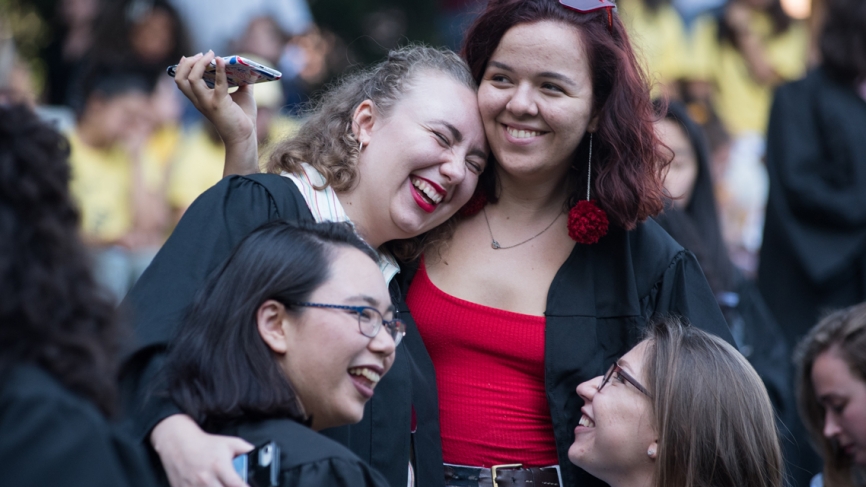 Four students laugh and hug