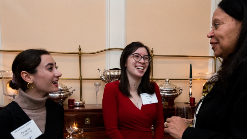 A student in a red shirt laughs with a dean and another student.