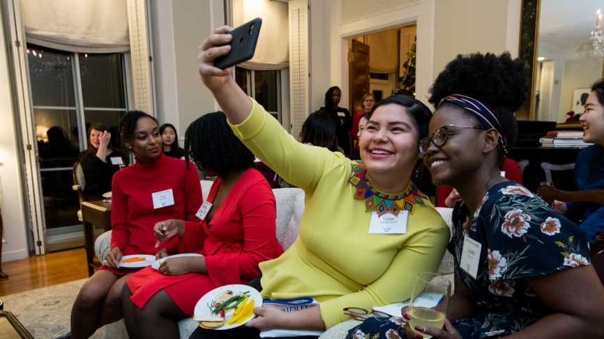 Students sit in the president's house, taking a selfie