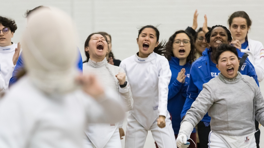 Members of the Wellesley fencing team cheer for a teammate on the sidelines.