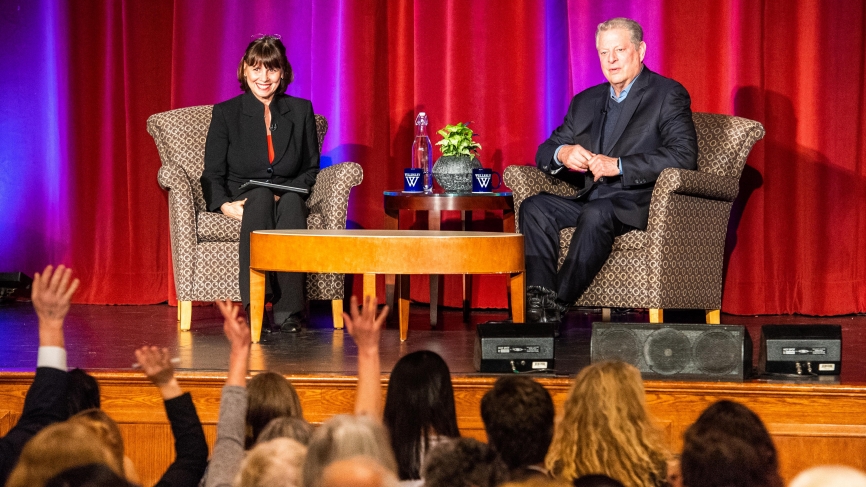Al Gore and Sue Wagner speak in front of a crowded alumnae ballroom.