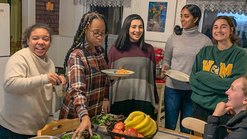 A group of students stand around a table, smiling