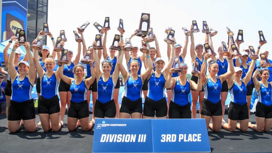 The Wellesley Blue crew team hold up trophies.