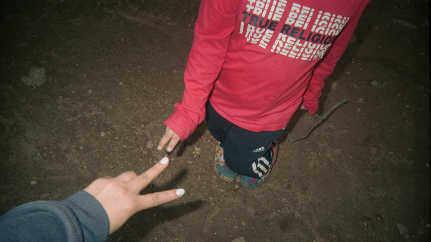 Two kids flash peace signs for the camera. Their faces are not visible.
