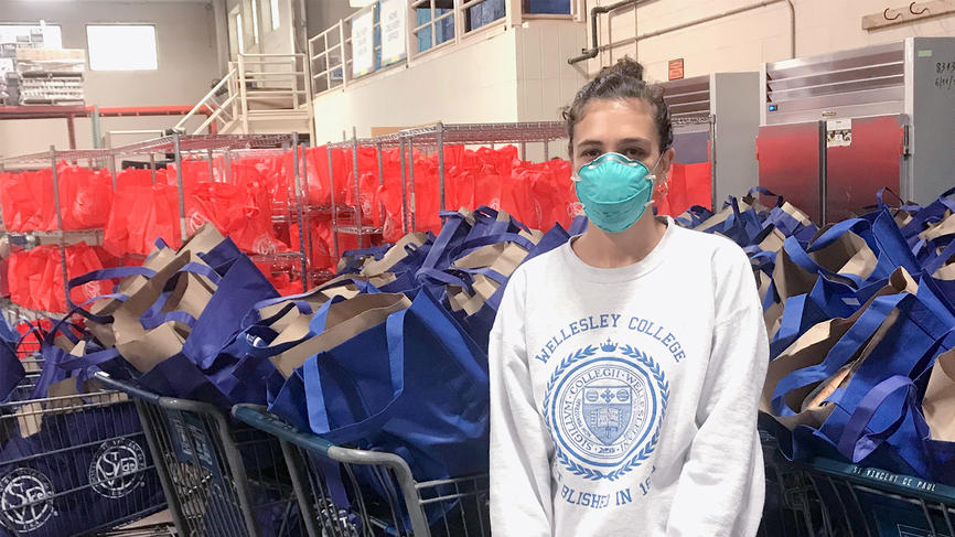 student wearing a mask standing in front of donation bags