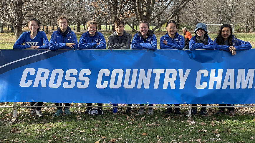 Members of the cross country team pose with a championship banner.