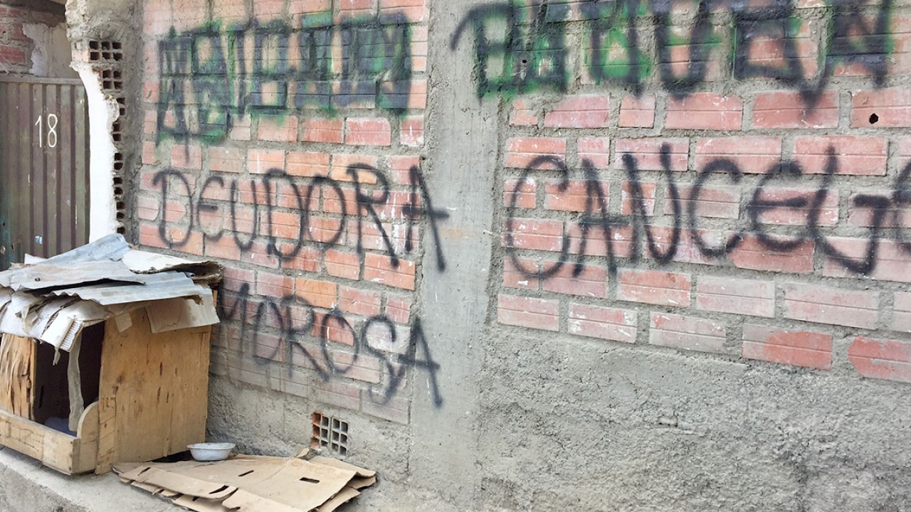 Graffiti on the wall of a house, which reads "Deudor moroso"