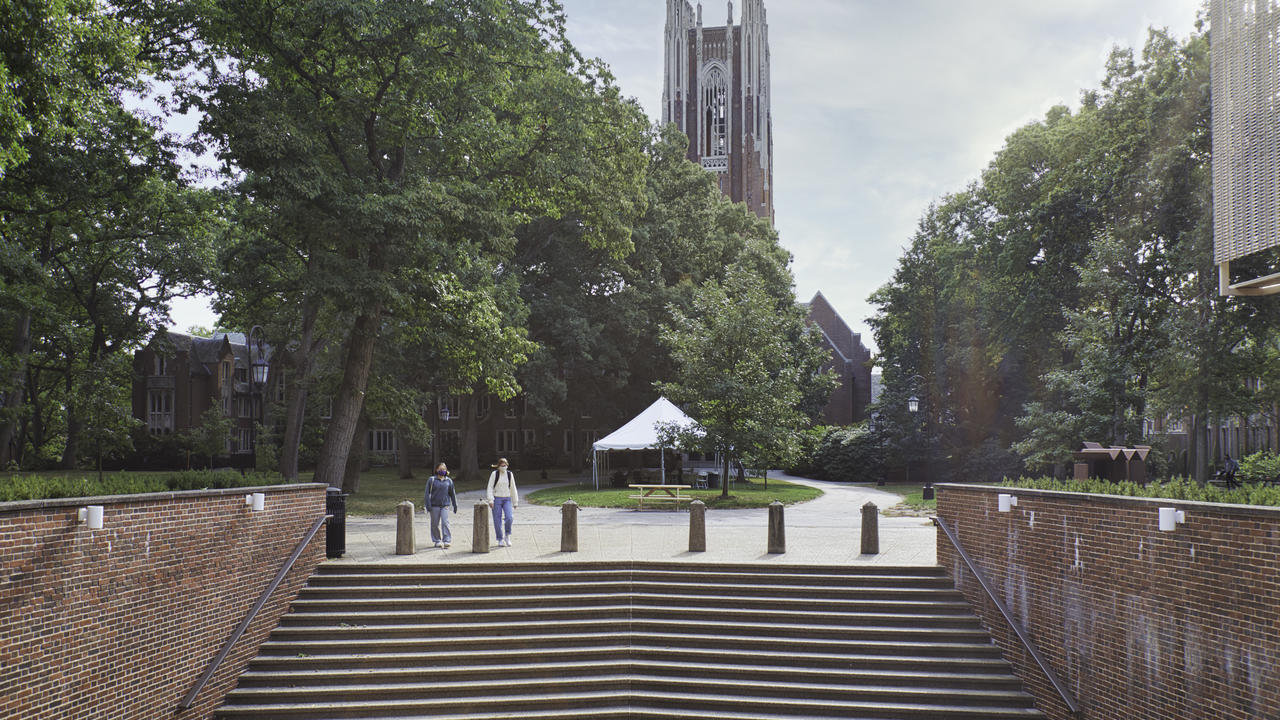 Wellesley College's Galen Stone Tower with the steps of Jewett Hall in the foreground and two students walking.