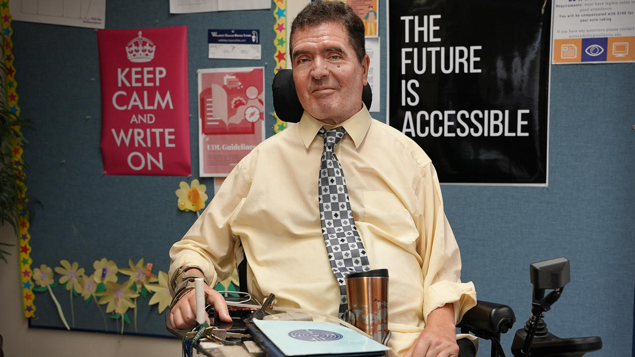 Jim Wice poses for a photo. Poster behind him reads The Future is Accessible.