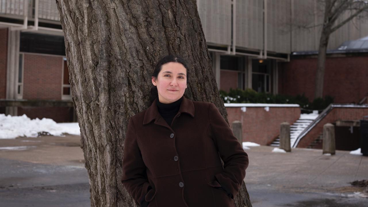 Woman stands outside in front of a tree