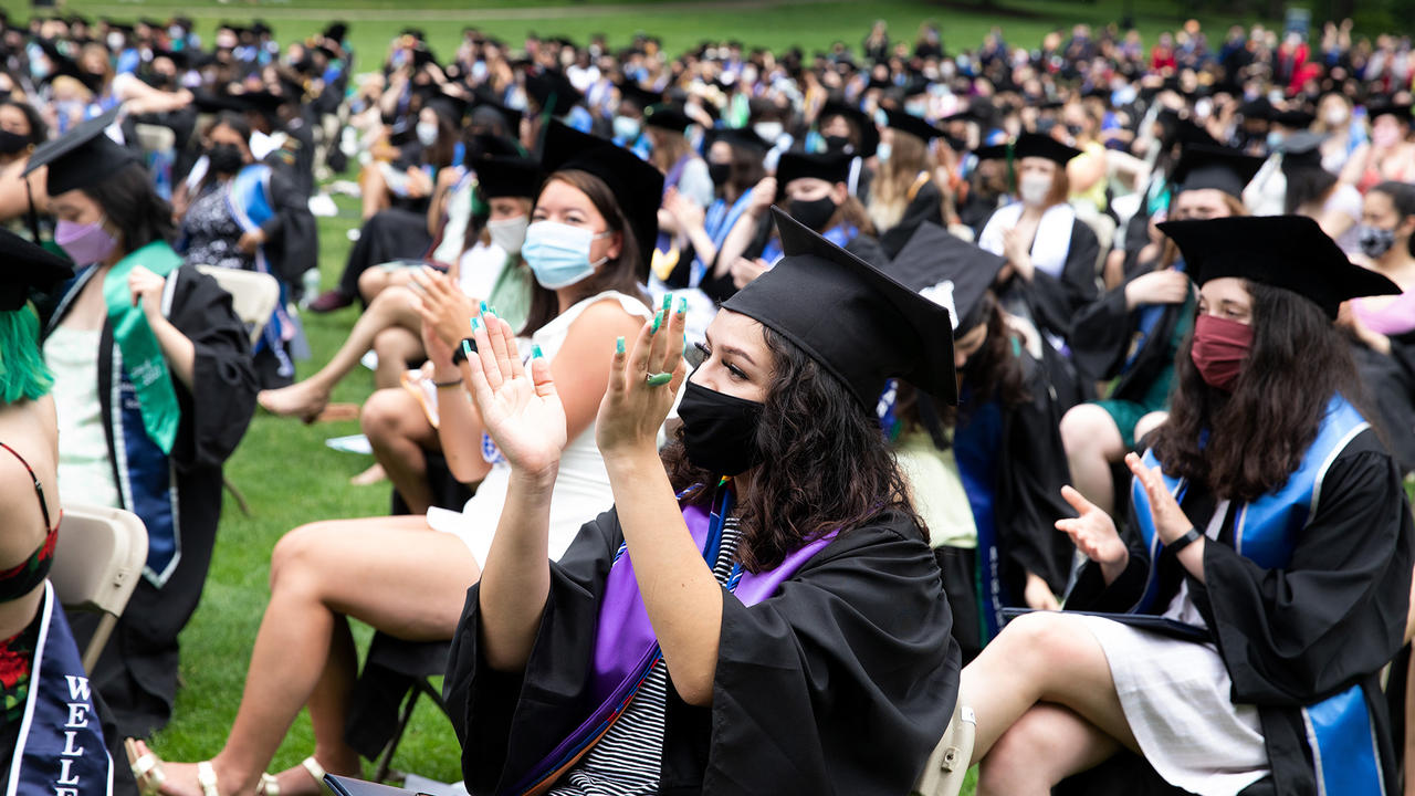 Students seated in the audience during commencement, applauding.