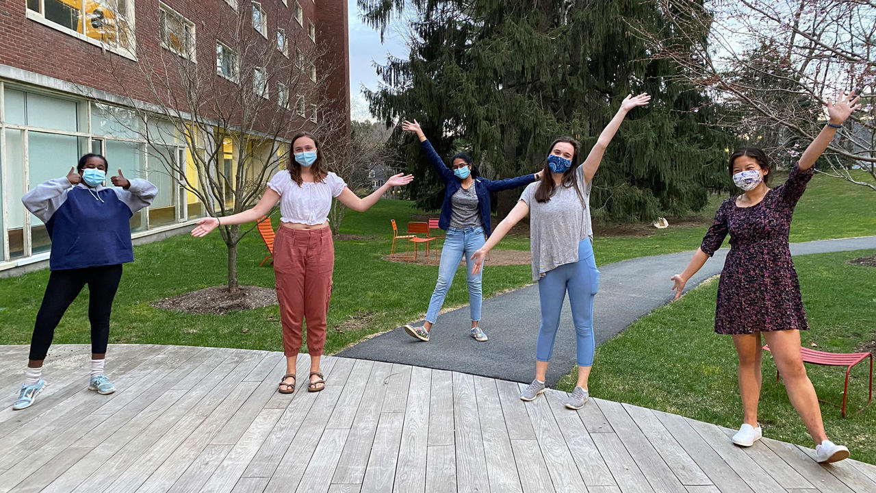 people wearing masks and posing with their hands up in the air