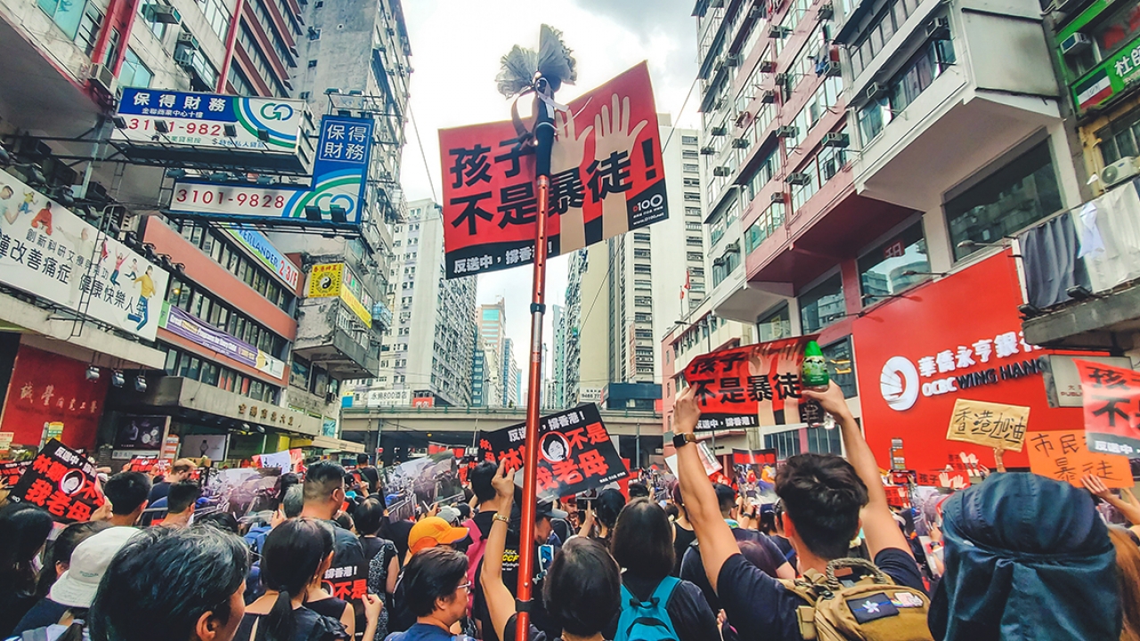 Protestors stand in a street in Hong Kong with signs.